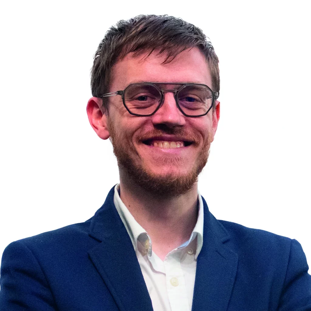 Un homme souriant en costume bleu, les bras croisés.